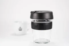 Glass thermal mug with a black lid and black rubber holder, 340 ml capacity, with a cup of coffee