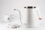 Open 0.7l Timemore Fish Pure Over fast-boiling kettle in white, on a white background with a lid and a porcelain cup with coffee motifs; Gooseneck kettle