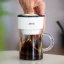 The Trinity Zero white drip coffee maker offers a capacity of 100 ml for brewing delicious coffee.