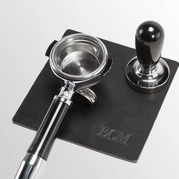 Leather mat with portafilter and coffee tamper.