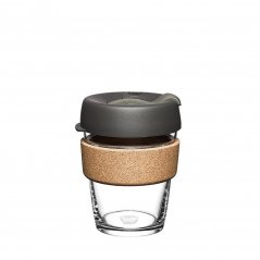 Taza de café de cristal Keepcup con soporte de corcho y tapa gris.